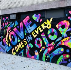 a large colorful graffiti wall on the side of a building with words written in different colors