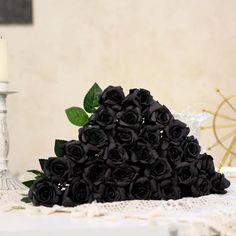 a bouquet of black roses sitting on top of a table next to a lit candle