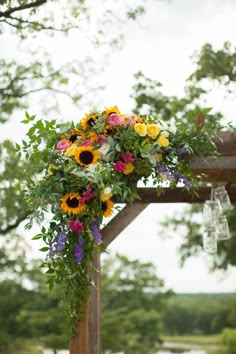 a wedding arch decorated with sunflowers and greenery