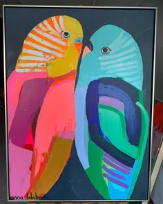 a painting of two colorful birds sitting next to each other on a black background with silver frame