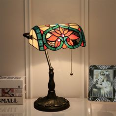 a lamp that is sitting on top of a table next to some books and pictures