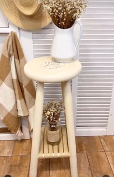 a small table with flowers on it next to a hat rack and towel racks in front of a window