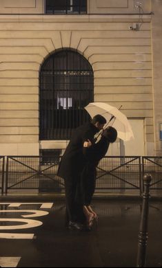 a couple kissing under an umbrella in the rain