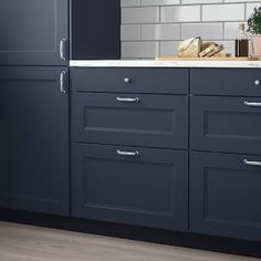 a kitchen with dark blue cabinets and white counter tops is seen in this image from the side view