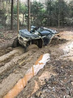 an off - road vehicle is stuck in the mud on a muddy path near some trees