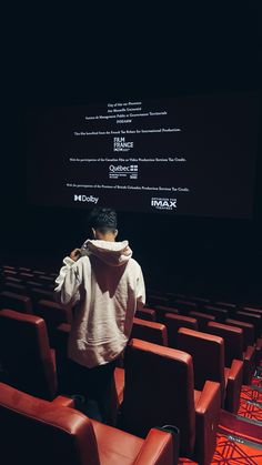 a man standing in front of a screen with his back to the camera and covering his face