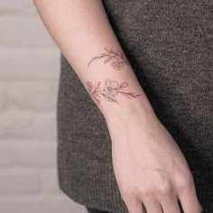 a woman's arm with a small flower tattoo on the left side of her wrist