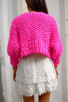 a woman wearing a pink sweater and white skirt