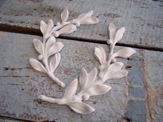 a close up of a white flower decoration on a wooden surface with bricks in the background