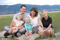 a family sitting on a blanket in the grass