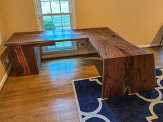 a wooden desk sitting on top of a hard wood floor in front of a window