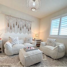 a living room filled with furniture and a chandelier hanging above the couches