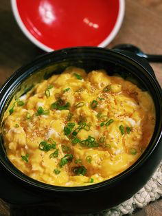 a black bowl filled with macaroni and cheese on top of a wooden table