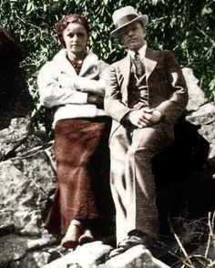 an old black and white photo of two people sitting next to each other on rocks