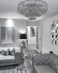 a black and white photo of a living room with chandelier above the couch