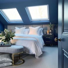 a bedroom with two skylights above the bed and a bench in front of it