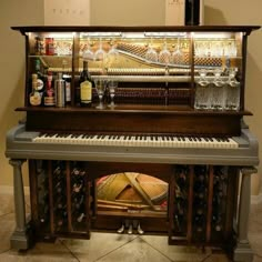 an old piano with wine glasses and bottles on it's shelf next to a bottle rack