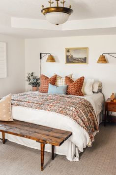 a bed sitting in a bedroom next to a wooden table and two pictures on the wall