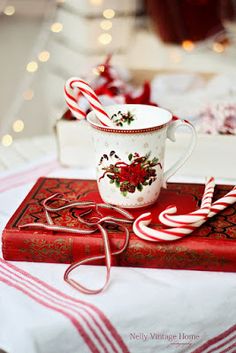 a cup with candy canes on top of it next to a red and white book