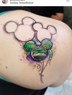 a tattoo on the back of a woman's shoulder with mickey mouse head and green paint