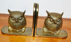 two brass owl bookends sitting on top of a wooden table