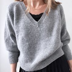 a woman wearing a gray sweater and black skirt