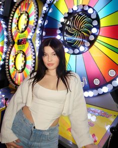 a woman standing in front of a colorful wheel of fortune machine with her hands on her hips