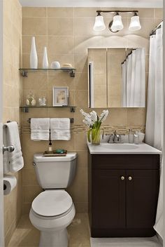 a white toilet sitting next to a sink in a bathroom under a mirror and lights