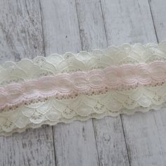 a pink and white lace ribbon on a wooden surface with wood planks in the background