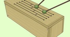 a wooden box with two green balls on it and some sticks sticking out of the top