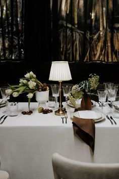 the table is set with white linens and place settings for two people to sit at