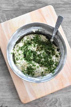 a metal bowl filled with food on top of a wooden cutting board