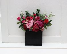 a black vase with red and pink flowers in it