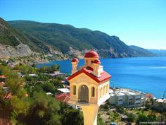 an aerial view of a small church on the side of a hill overlooking a large body of water