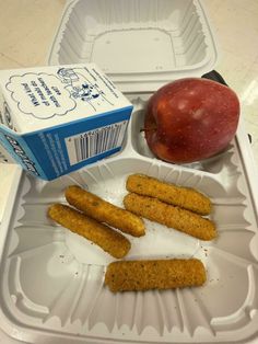 an apple, crackers and yogurt are on a plastic tray next to a carton of milk