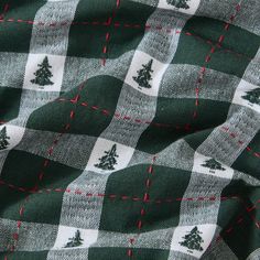 a green and white checkered fabric with trees on the front in red stitching