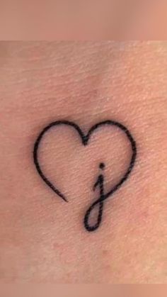 a small heart tattoo on the side of a woman's stomach with an arrow in it