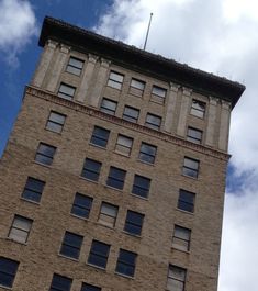 a tall brick building with lots of windows and a clock on the top of it