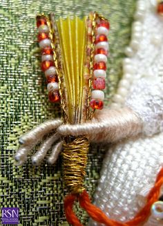 an orange and white beaded brooch sitting on top of a piece of cloth