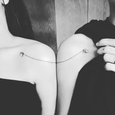 two women with small tattoos on their backs, one is holding the other's arm