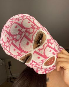 a woman wearing a pink and white knitted mask with eye holes in the middle