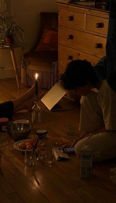 two people sitting on the floor in front of a candle