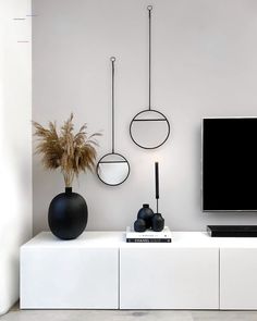 a flat screen tv sitting on top of a white entertainment center next to a plant