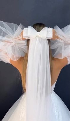 the back of a bride's head with veils on her shoulders and arms