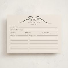 a recipe card on a white wall with a ribbon tied around the top and an empty note attached to it