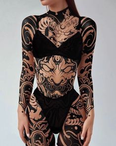 a woman in black bodysuit with tattoos on her chest