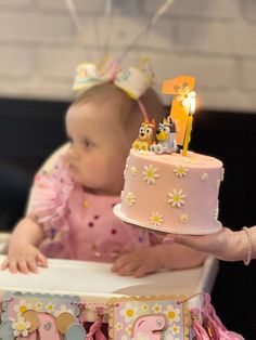 a baby sitting in a high chair with a cake