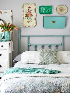 a white bed topped with lots of pillows next to a wall covered in framed pictures