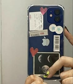 a person holding up a cell phone with stickers on it's back cover