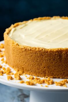 a cake with white frosting sitting on top of a white plate covered in orange crumbs